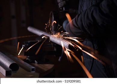 Metalworker Cutting Metal Pipe With A Electric Rotary Angle Grinder On An Working Table And Generating Metal Sparks