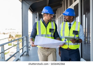 Metalworker and engineer meeting at construction site. Multiethnic architects site with safety equipment walking and discussing. Architect and engineer working together while visiting a new building. - Powered by Shutterstock