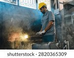 Metalworker forge workshop hard hat glove metal spark smoke worker safety gear at industrial foundry with focused man shaping hot material amid tool and machinery