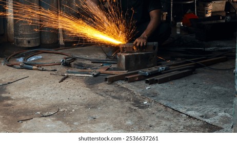 Metalworker grinding metal with an angle grinder, creating bright sparks in a dark workshop. Industrial setting with tools and equipment in the background - Powered by Shutterstock