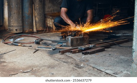 Metalworker grinding metal with an angle grinder, creating bright sparks in a dark workshop. Industrial setting with tools and equipment in the background - Powered by Shutterstock