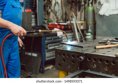 Metalworker heating up piece of metal with burner in his workshop - Powered by Shutterstock