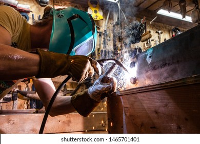 Metalworker operates spot welder indoors. A closeup view of a skilled tradesman operating a metal inert gas welder to join the corners of two steel beams. Process of a metalworker at work. - Powered by Shutterstock