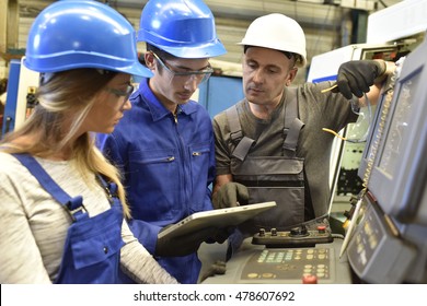 Metalworker with training people using electronic machine