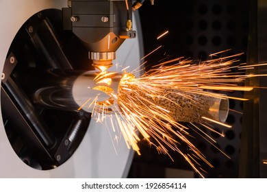 Metalworking, equipment, machining, industrial, technology, manufacturing concept. Automatic cnc laser cutting machine working with cylindrical metal workpiece with many sparks at factory, plant