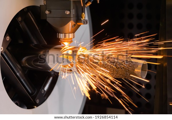 Metalworking, equipment, machining, industrial,\
technology, manufacturing concept. Automatic cnc laser cutting\
machine working with cylindrical metal workpiece with many sparks\
at factory, plant