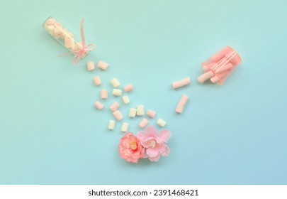 Metaphorical concept of care for flowers. Pink flower sprayed with marshmallows from small transparent tanks on a pastel blue background. Minimal flat lay composition. Top view - Powered by Shutterstock