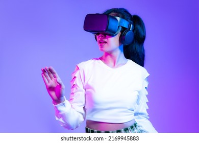 Metaverse concept, young asian girl in white fashion sweatshirt wearing vr headset playing hand touching online game on purple background. - Shutterstock ID 2169945883
