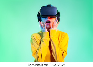 Metaverse Concept, Young Asian Woman In Yellow Sweatshirt Wearing Vr Headset Playing Watching Exciting On The Green Screen Background.