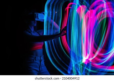 Metaverse digital Avatar, Metaverse Presence, digital technology, cyber world, virtual reality, futuristic lifestyle. Woman in VR glasses playing AR augmented reality NFT game with neon blur lines - Shutterstock ID 2104004912