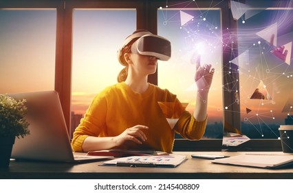 Metaverse technology concept. Woman with VR virtual reality goggles is working in the office. Futuristic lifestyle. - Shutterstock ID 2145408809