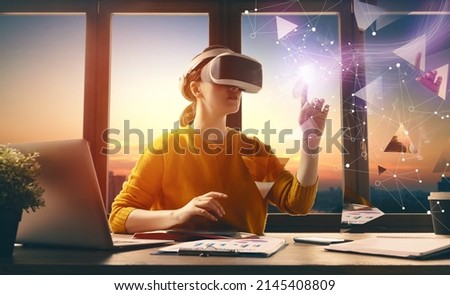Metaverse technology concept. Woman with VR virtual reality goggles is working in the office. Futuristic lifestyle.
