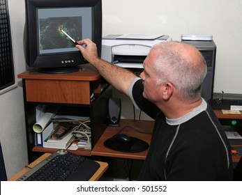 A Meteorologist Tracking A Hurricane On His Computer And Pointing Out The Eye. (focal Point Is His Head/face)