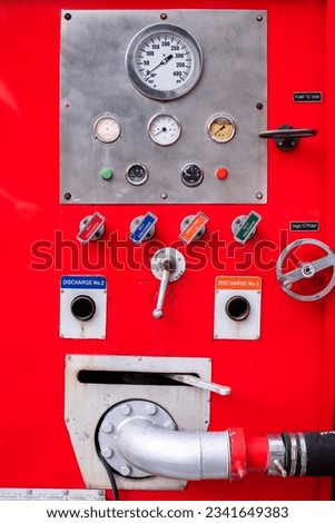 Meter and control switch are fire equipment on a red fire truck.