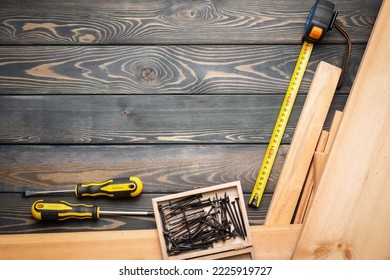 Meter, screwdriver, screws and wooden bars on the carpenter workbench background with copy space. - Shutterstock ID 2225919727