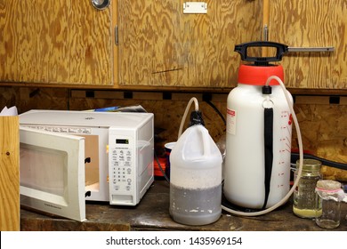 Meth lab on a garage work bench consisting of a plastic bottle, a chemical sprayer, and jars of solvents