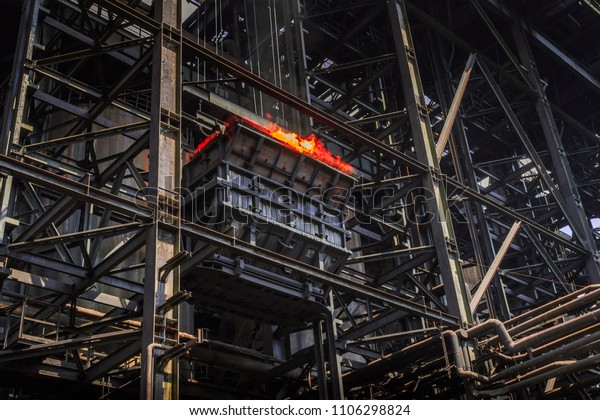 Method\
of burning coke - solid fuel made by heating coal. Flames in a\
carriage is pulled up on scaffolding in\
ironworks.
