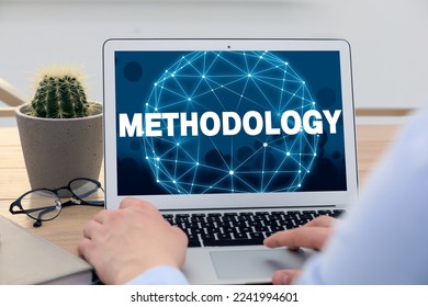 Methodology concept. Man using modern laptop at table indoors, closeup