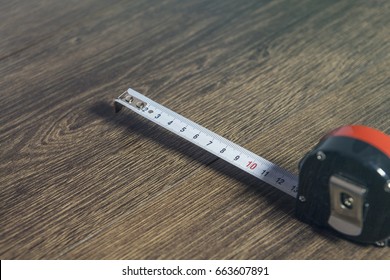 Metric measuring tape opened with white black numbers on white on wooden surface