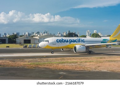 Metro Manila, Philippines - May 2022: A Cebu Pacific Airplane On The Tarmac Ready For Takeoff Awaiting Go Signal From Air Traffic Control. Makati Skyline In The Background.