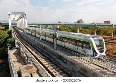 A metro train of Taichung MRT (Mass Rapid Transit) dashing through a bridge near the High Speed Rail Station on a beautiful sunny day, in Wuri District, Taichung City, Taiwan