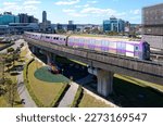 A metro train of Taoyuan Airport MRT travels on the elevated railway track, with high rise buildings booming in the Industrial Park in background, in Xinzhuang District, New  Taipei City, Taiwan, Asia