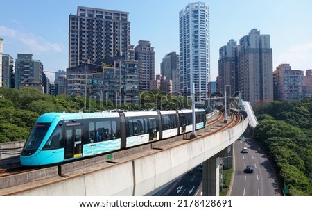 A metro tram dashing on the elevated track of Danhai Light Rail Transit near Ganzhenlin Station, with booming residential towers in the nearby community, in Tamsui District, New Taipei City, Taiwan