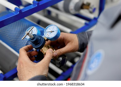 A metrology laboratory specialist takes a compressed gas cylinder for testing and verification. The man connects the pressure gauge. Analyze gas and check connections for leaks.