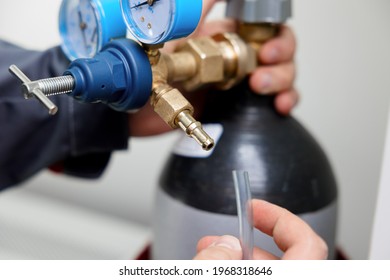 A Metrology Laboratory Specialist Takes A Compressed Gas Cylinder For Testing And Calibration With A Chromatograph. A Man Connects A Hose For Gas Analysis. Gas Analyzer And Chromatography.