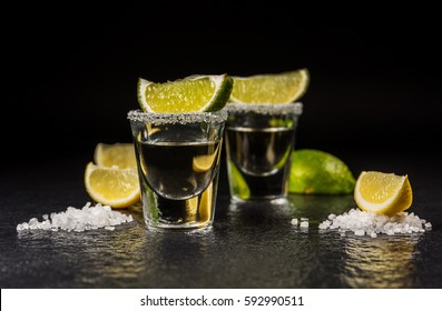 Mexican Alcoholic Drink Tequila With Salt And Lemon Or Lime On Black Stone Table