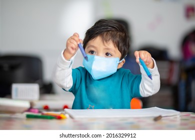 Mexican Baby In School With Face Mask Playing And Drawing With Crayons