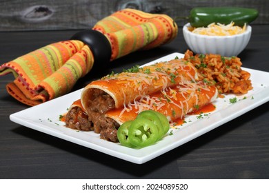 Mexican Beef Enchiladas On A Plate With A Serving Of Tex Mex Rice.  Macro View.