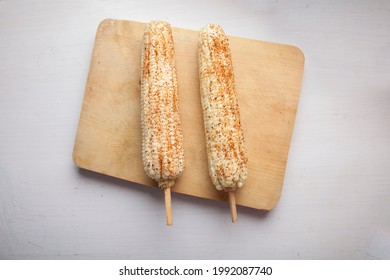 mexican boiled white corn on the cob with chili, lime and mayonnaise on wooden table 