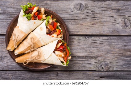 Mexican burrito with chicken , pepper and beans . Top view , space for text