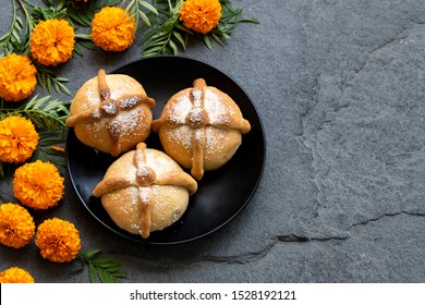 Mexican celebration, bread of death. Mexican parties with Dead bread and marigold flowers on gray stone background. Traditional Mexican Bread of the Dead Pan de Muerto .