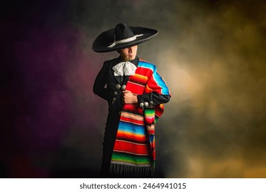 Mexican charro with hat and multicolored serape A man wearing a sombrero and a colorful blanket. The man is standing in front of a blurry background