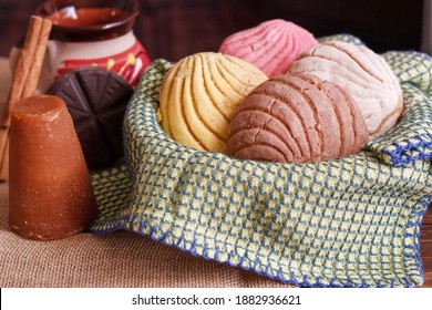 mexican conchas bread inside of a tray with a cup of hot chocolate 