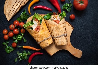 Mexican Corn Tortilla Wrap With Grilled Chicken And Fresh Vegetables Served On A Wooden Cutting Board. Dietary Healthy Dish. Black Background, Flat Lay, Copy Space