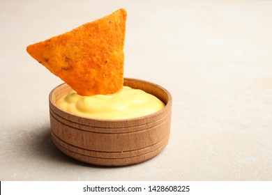 Mexican crispy snack, nachos chips and cheese sauce on neutral background.