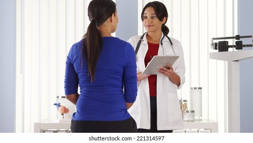 Mexican doctor talking to African American patient using pad