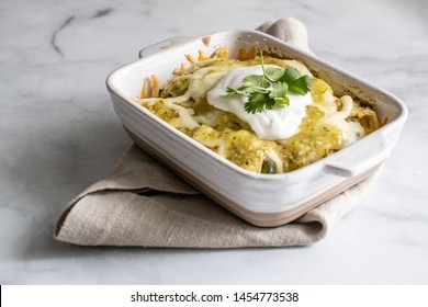 Mexican Enchilada In A Casserole Dish. Fine Mexican Homemade Dish From A Flat Lay And 15 Degree Angle. Garnished With Fresh Cilantro As The Dish Sets On A White Marble Table. 