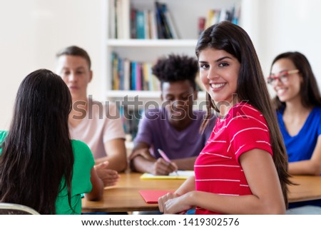 Mexican female student learning with group of students at classroom of college