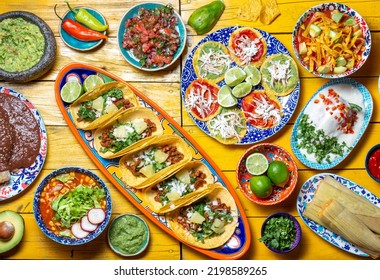 Mexican festive food for independence day - independencia chiles en nogada, tacos al pastor, chalupas pozole, tamales, chicken with mole poblano sauce. Yellow background - Powered by Shutterstock