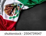 Mexican Flag on Black Background. A close-up of the Mexican flag draped on a black surface, with a focus on the intricate details of the flag