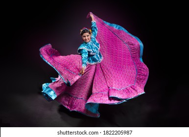 Mexican Folk Dancer Woman From The State Of Nayarit, Mexican Pink Nayarrita Folk Costume With Blue, Fan And Dancing With Skirt And Turns On Black Background