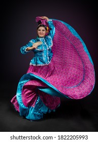 Mexican folk dancer woman from the state of nayarit, Mexican pink nayarrita folk costume with blue, fan and dancing with skirt and turns on black background