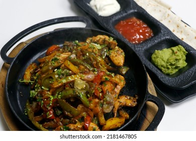 Mexican Food, Chicken Fajitas Serving On A Hot Smoking Sizzling Plate With Sour Cream, Guacamole, Tomato Salsa And Tortilla Bread