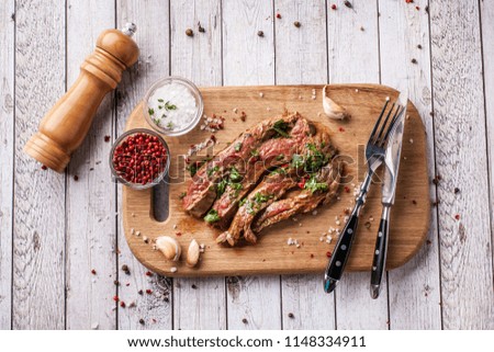 Mexican food. The girl has a fillet of meat steak with the addition of spicy green salsa. meat on a wooden board. Knife and fork in hands. concept of a beautiful dish in a restaurant. selective focus