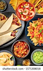 Mexican Food, Many Dishes Of The Cuisine Of Mexico, Flatlay, Top-down Shot On A Black Background. Shrimp Cocktail, Nachos, Guacamole, Burritos, Chili Con Carne