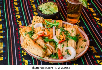 Mexican Food. Plate Of Tamales With Herbs And Chilies On Top. Mexican Table Cloth On The Background.